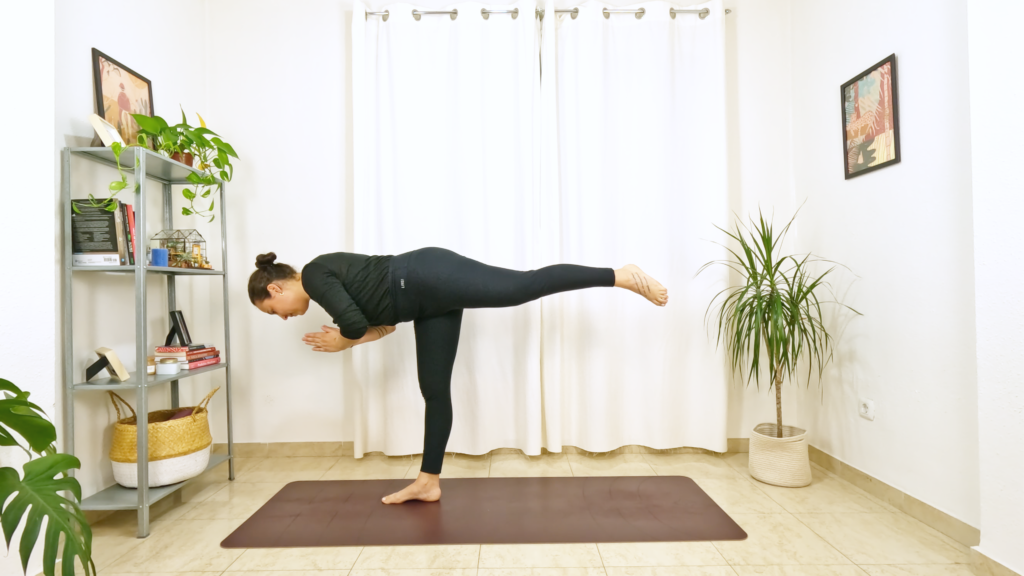 Mulher em postura de yoga equilibrando em um pé com a outra perna esticada elevada e tronco paralelo ao chão