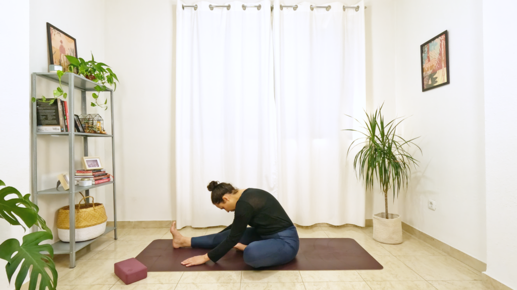 Mulher em postura de yoga sentada com uma perna esticada e a outra dobrada com sola do pé encostando o interior da coxa oposta