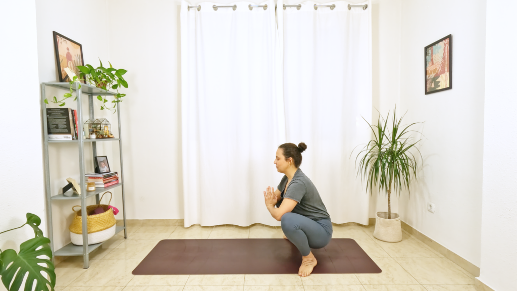 Mulher em postura de yoga com joelhos dobrados e afastados, e cotovelos encaixados no interior dos joelhos