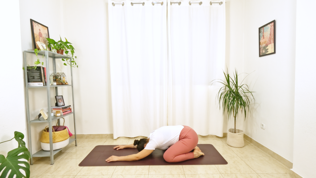 Mulher em postura de yoga sentada sobre os calcanhares e testa apoiada no chão