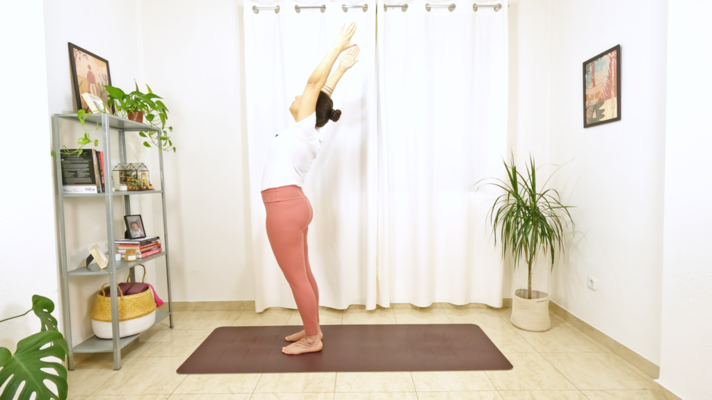 Mulher em uma postura de yoga em pé , com os braços elevados e arqueando a coluna.