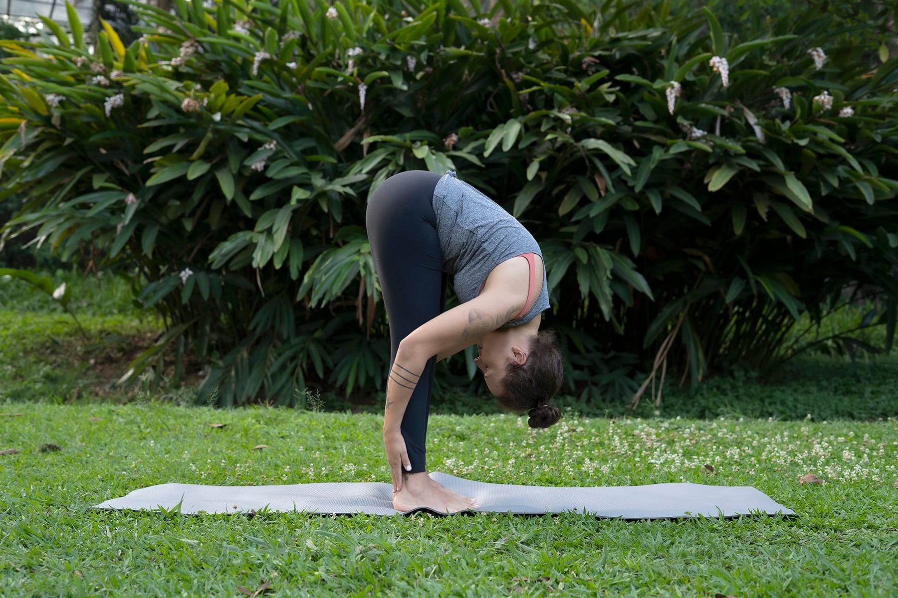 Foto de uma mulher em pé com o tronco flexionado pra frente, alongando as pernas