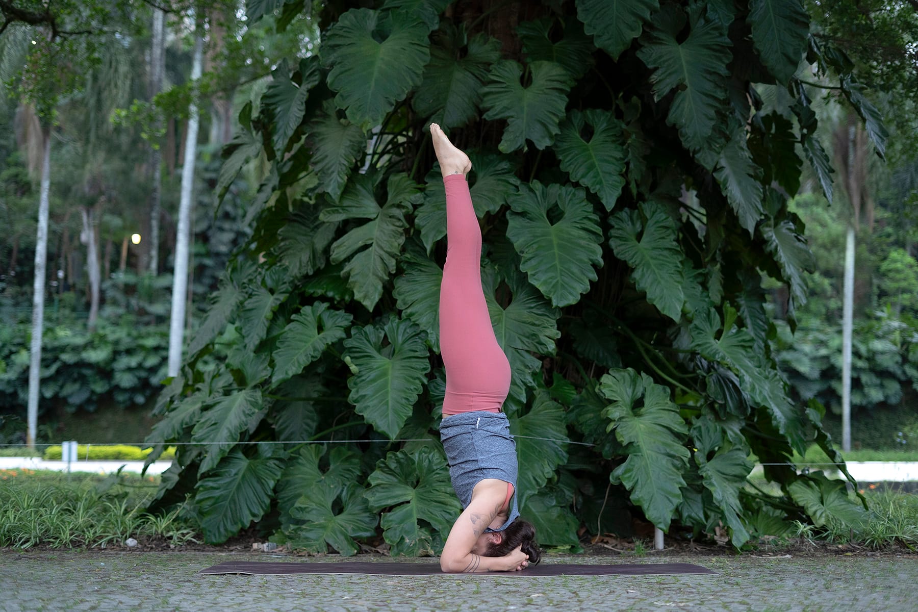 Mulher em postura invertida de yoga com cabeça e braços apoiados no chão