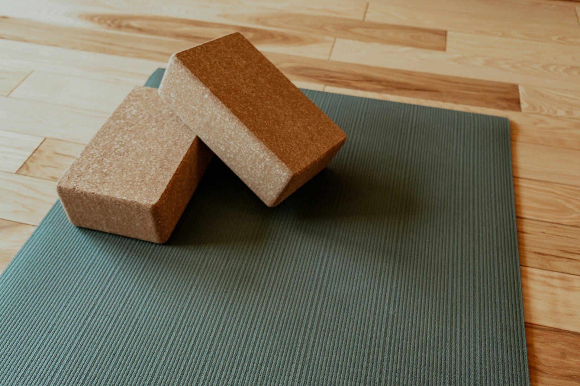 Foto de 2 blocos de yoga em cima de um tapete de yoga verde