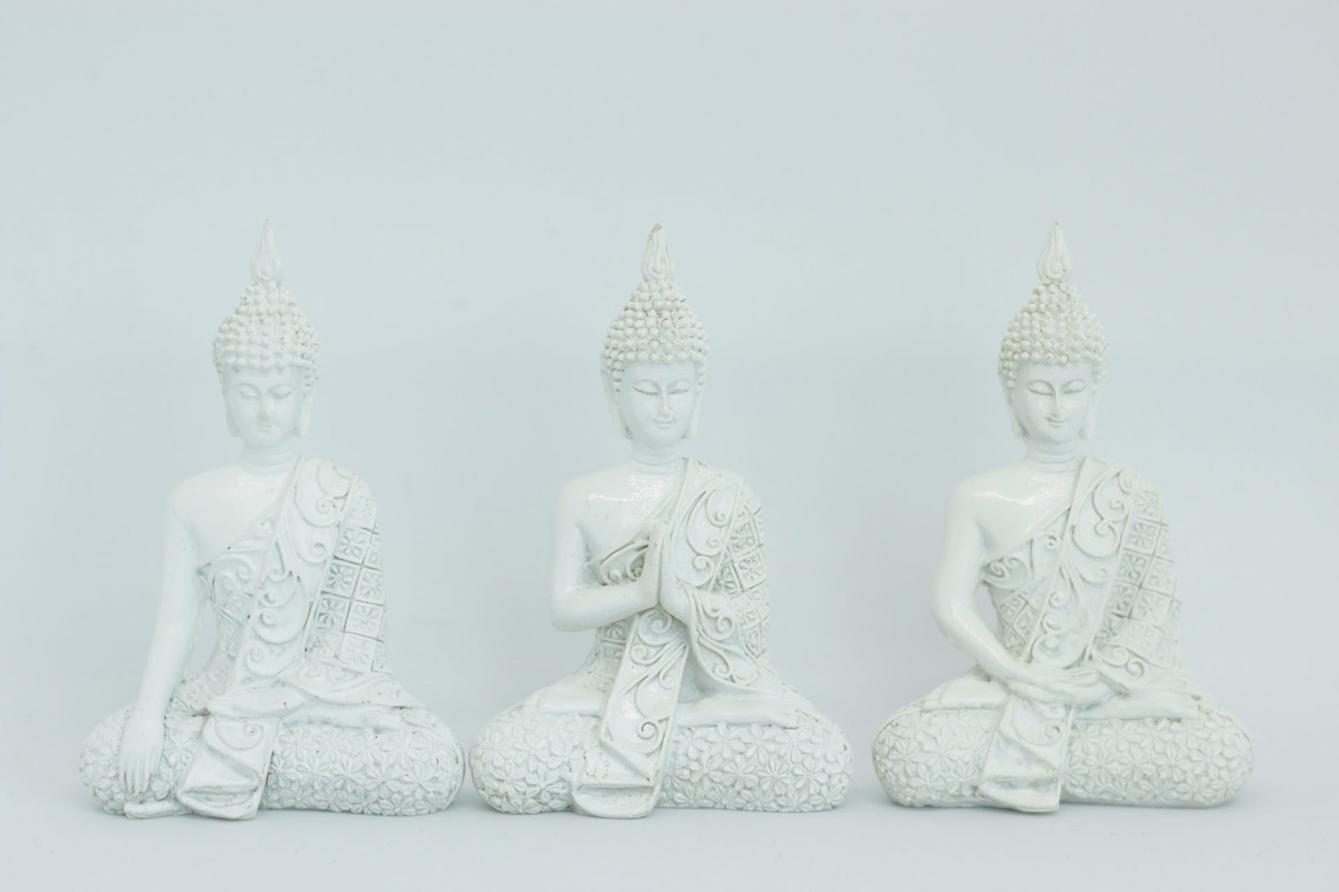 Foto de 3 estatuas brancas em posturas meditativas