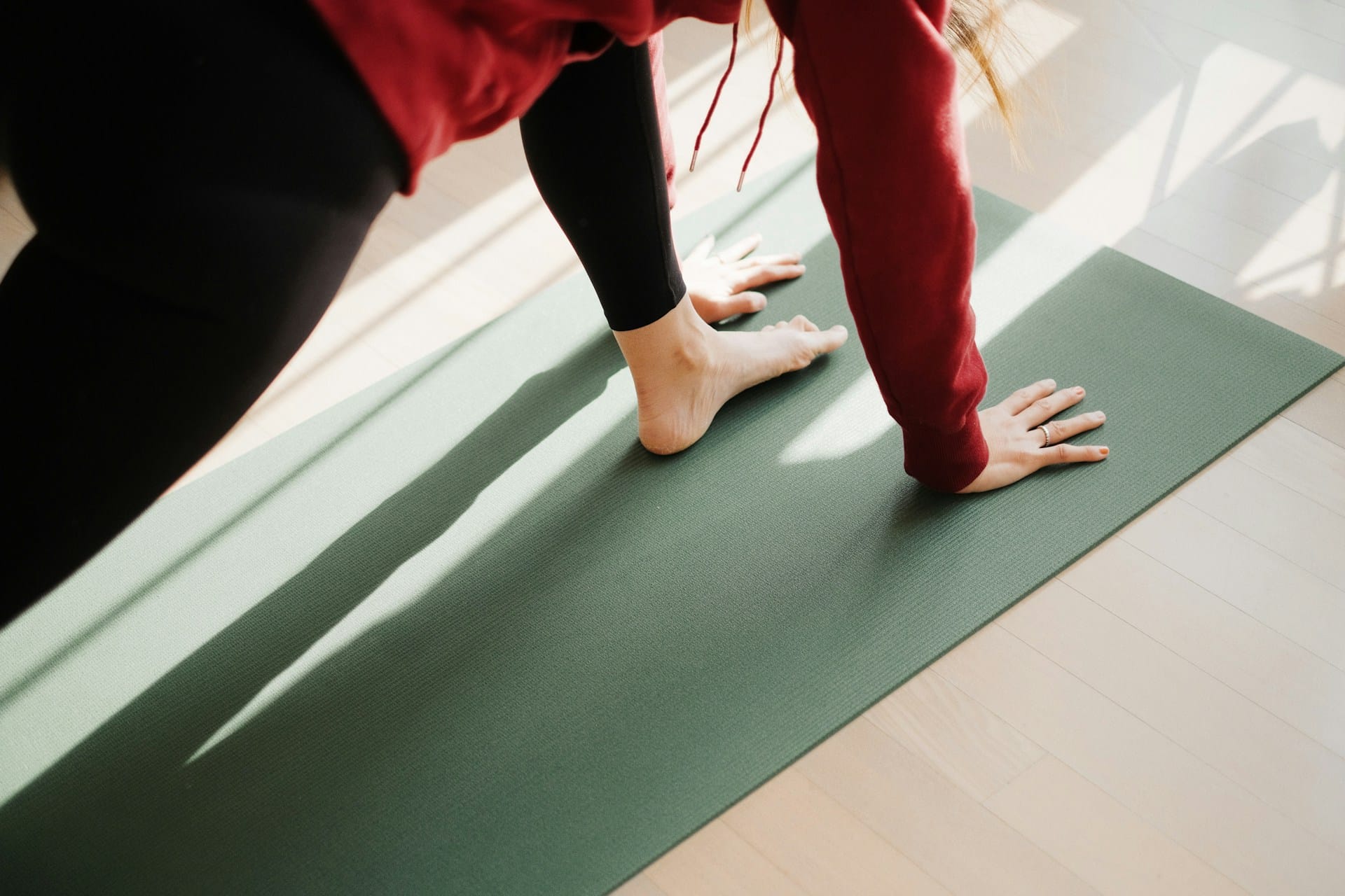 Foto de mulher em postura de yoga com uim pé apoiado na frente, as mãos apoiadas no chão e o outro pé apoiado atrás.