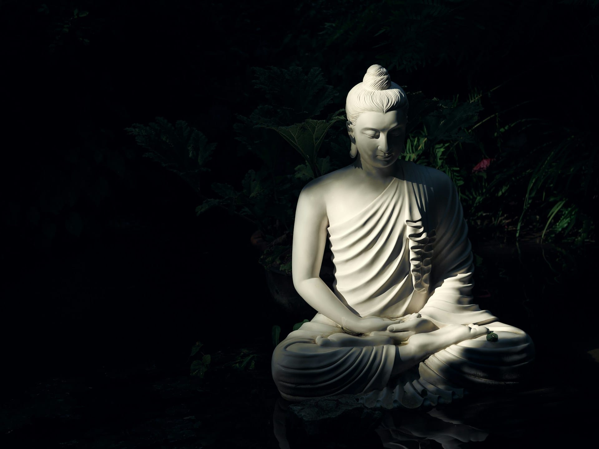 Foto de uma escultura branca em posição de meditação