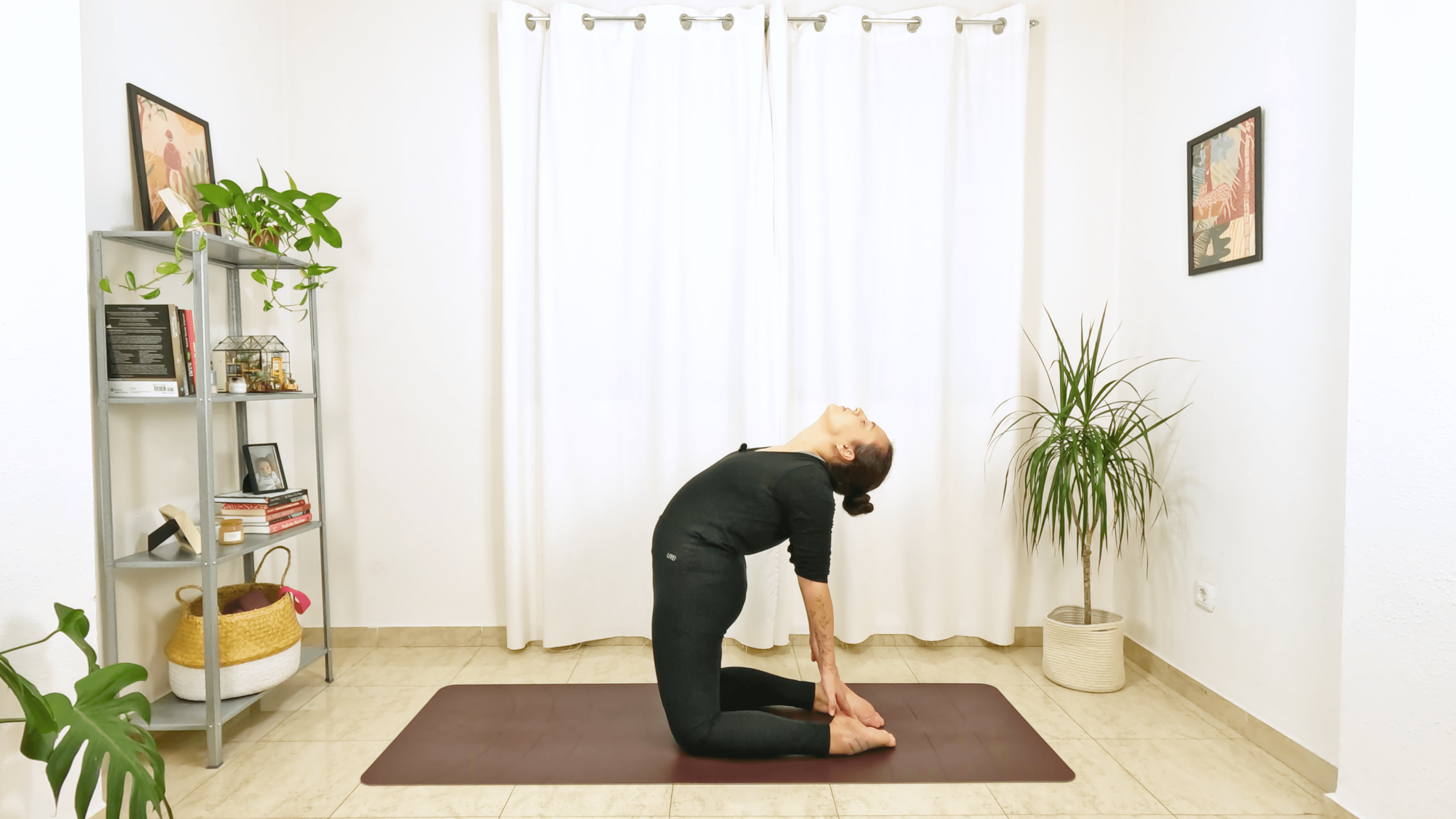 Mulher em postura de yoga com joelhos apoiados no chão, segurando os calcanhares com as mãos arqueando a coluna